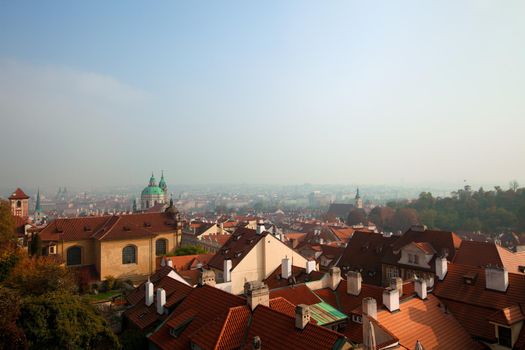Old Prague roofs at autumn morning with smoke from pipe