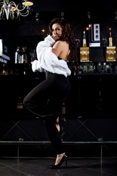 Beauty woman stand near bar in retro luxury white fur coat