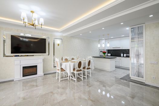 Luxury white large domestic kitchen with glossy marble floor, kitchen island and dining table