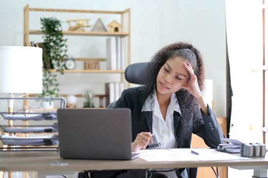 Serious african american businesswoman sitting at table looking at laptop screen. Ethnic woman read message email with important news, business documents online, chatting with clients working remotely.