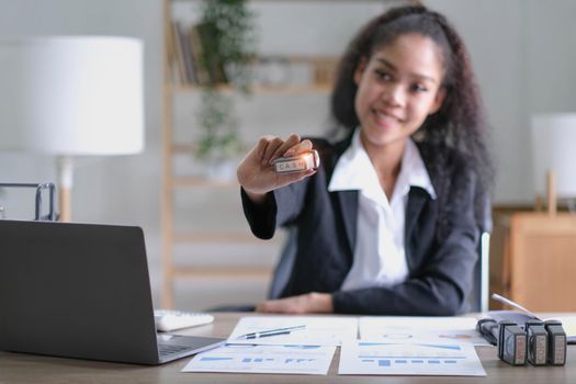 Focused millennial Black business woman calculating finance, money, using calculator, laptop computer at home workplace table, counting budget, paying bills, taxes, rent, mortgage fees.