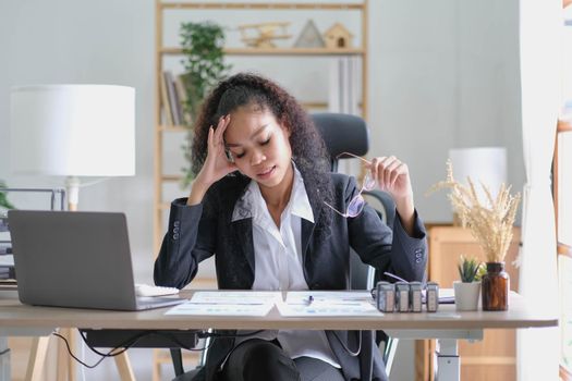 Serious african american businesswoman sitting at table looking at laptop screen. Ethnic woman read message email with important news, business documents online, chatting with clients working remotely.