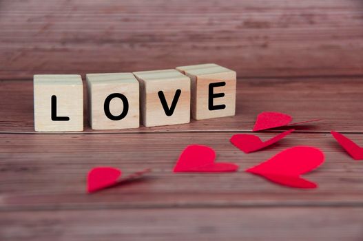 Love text on wooden blocks with heart shape and wooden background. Romance and relationship concept.