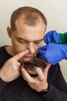 A nurse rinses the nasal cavity of a patient suffering from sinusitis with saline solution using a syringe.