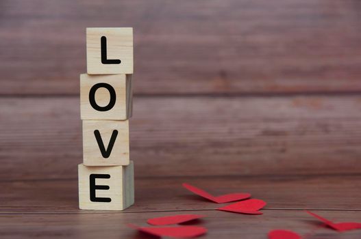 Love text on piled up wooden blocks with heart shape and wooden background. Romance and relationship concept.