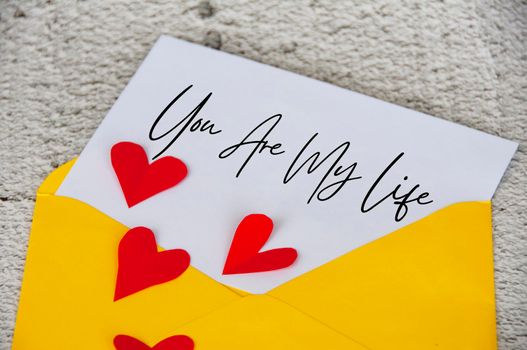 You are my life text on notepad in yellow envelope surrounded with heart shape. Romance and relationship concept.