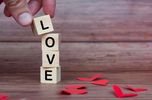 Love text on wooden blocks with heart shape and wooden background. Romance and relationship concept.
