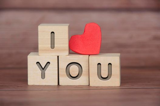 I Love You text engraved on wooden blocks with heart shape and wooden background. Romance and relationship concept.