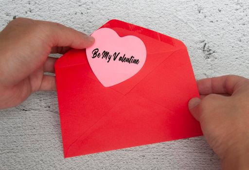 Be my valentine text on heart shape notepad in red envelope. Romance and relationship concept.