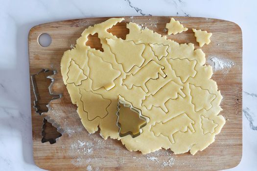 the process of cutting figures from shortcrust pastry for cookies with forms in the form of Christmas trees and animals