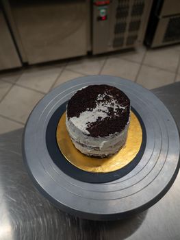 Decorator using spatula and scraper to smooth buttercream on a frosted cake