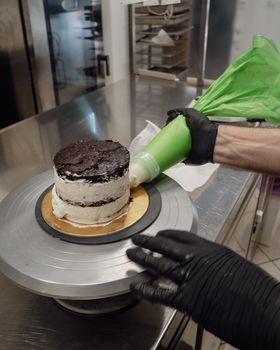 decorator applying buttercream to frosted cake with bag full of cream
