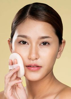 Closeup ardent woman applying her cheek with dry powder and looking at camera. Portrait of younger with perfect makeup and healthy skin concept.