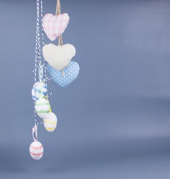 Home decor for Easter. Bright Easter eggs hanging on strings on a gray background, copy space