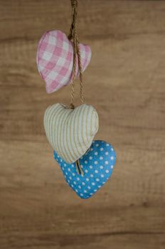 Fabric colorful hearts hanging on brown wooden wall. Happy Valentines Day