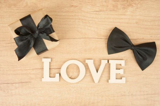 wooden word LOVE with butterfly tie and gift box on wood table. Happy father's day 