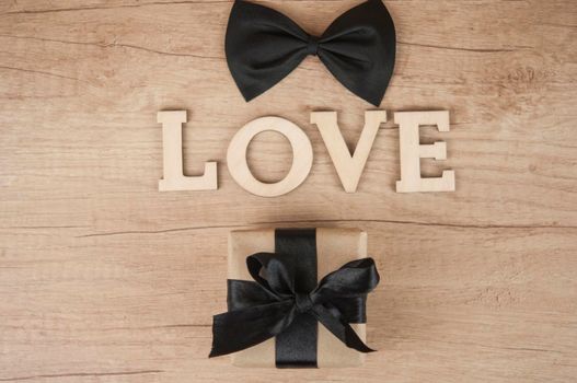 wooden word LOVE with butterfly tie and gift box on wood table. Happy father's day 