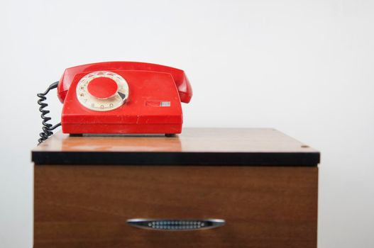 Retro rotary telephone on wooden table over white wall in room