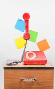 Urgent call waiting , classic red telephone receiver, old telephone on white background, flying in weightlessness with wooden desktop.