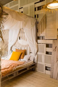 Modern home interior design. Bed with wooden canopy and pillows, blanket. Exotic bedroom interior, scandinavian style