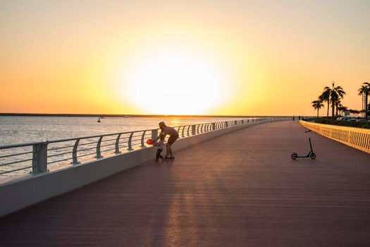 Children playing with balloon on boardwalk during sunset hour. Outdoors.