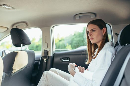 Tired female car passenger holding laptop in hands