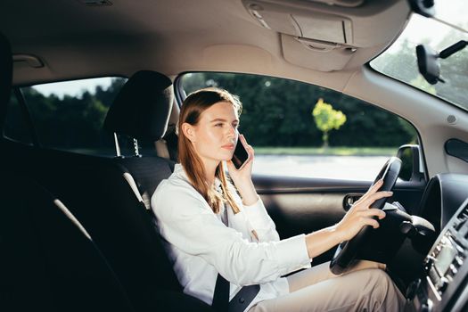 Female driver in a beautifully dressed businesswoman's car talking on the phone in the parking lot