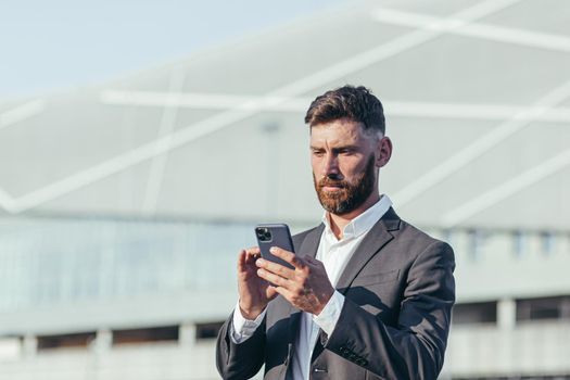 Businessman on the background of the office center is corresponding in a mobile phone