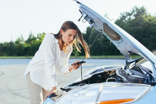 An annoyed and angry woman, near a broken car, tries to call an insurance agent and a repair crew. for car repair