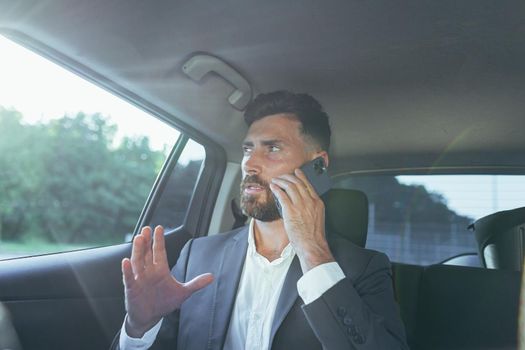 Close-up portrait of a man, a car passenger talking on the phone and looking out the open window