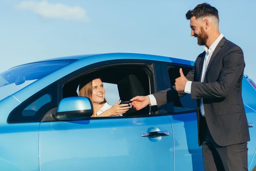 a man hands over the car keys to a woman sitting in the car