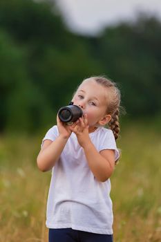 child drinking water from a bottle while outdoors