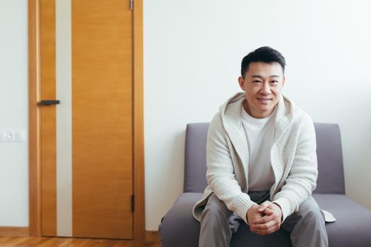 Young asian man got a good news sitting and smiling in the waiting room for interview results or tests at the clinic