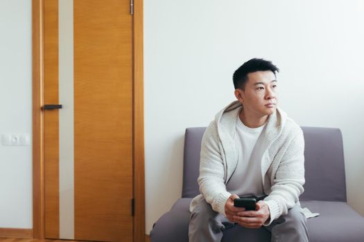 A young man is waiting in the hallway of a clinic or office center, talking on the phone and sharing news and the result of the interview, serious in everyday clothes