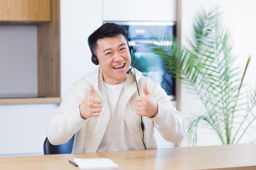 Asian man talking online on video call at home room with headset. Male in casual clothes looking at camera, meeting or conference in distance. Portrait student or teacher Lecture training. Webcam view