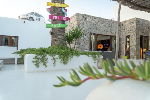 White and stone Ibizan hotel adorned with a vintage car on the rooftop