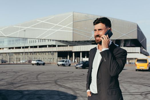 A man in a business suit is talking on the phone near the office center