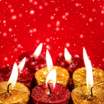 Winter, celebration and new years eve concept - Christmas candles and shiny snow on red background, holiday season decoration