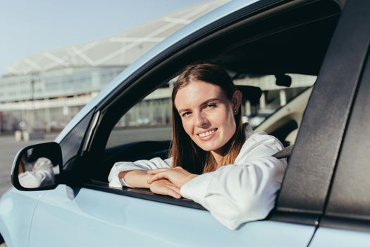 Portrait of a successful woman driving a car, smiling rejoicing and looking at the camera