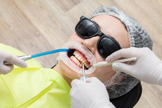 Patient with cheek retractor lying in dentist office in modern clinic