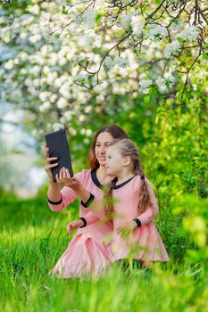 mother and daughter take pictures using a tablet in nature