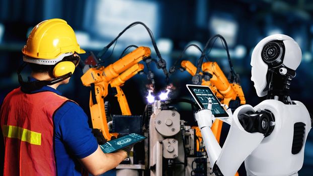 Cybernated industry robot and human worker working together in future factory . Concept of artificial intelligence for industrial revolution and automation manufacturing process .