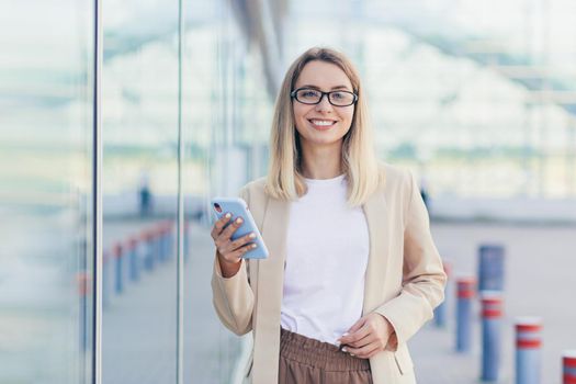 Beautiful woman holding a phone in her hands looking into the camera