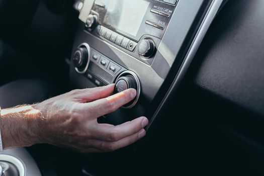 Male car driver tweaks air conditioner control close up photo