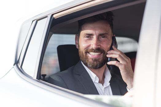 Close-up portrait of a man, a car passenger talking on the phone and looking out the open window