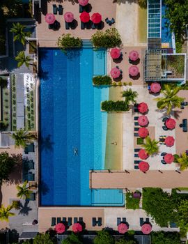 Aerial view from above at pool, tropical swimming pool from above with a drone. Men and women relaxing at a luxury pool during a honeymoon