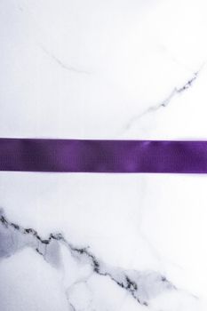 Happy holidays, festive decoration and brand sale promotion concept - Purple silk ribbon and bow on luxury marble background, holiday flatlay backdrop