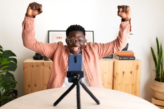 African American black male influencer live streaming with cellphone celebrating success with his followers. Social media concept.