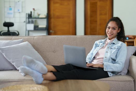 Portrait of an African American sitting on the sofa and working on a computer at home