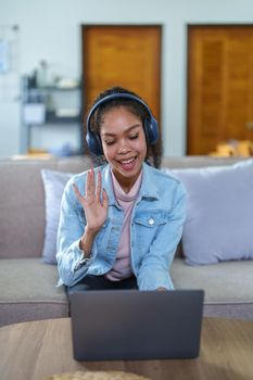 Portrait of an African American with headphones and a computer conferencing for a meeting over the Internet while working at home.